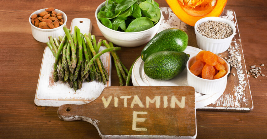 Foods containing vitamin E on a wooden board.